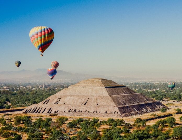 a group of hot air balloons flying over a pyramid