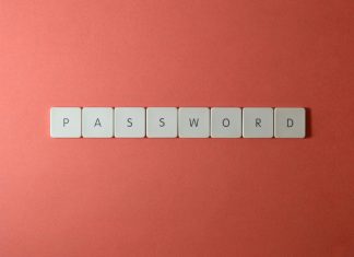 Focus on password security with white keyboard tiles spelling 'PASSWORD' on a coral background.